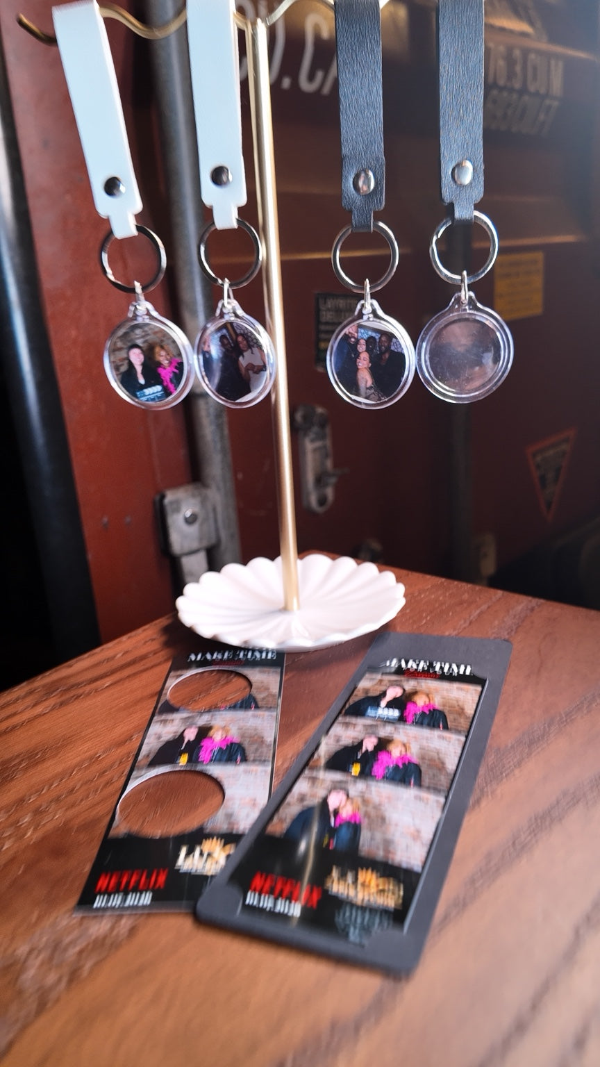 Round photo keychains with black and white straps displayed above event photo strips